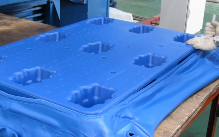 The middle photo describes an operator remove the residue from a blow-molded plastic pallet produced by blow-molded material through blow-modling production method. 
