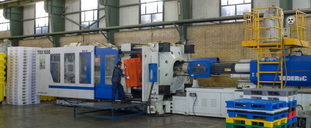 the photo show an injection machine that an operator take out an inject-molded pallet from the mold. the process is injection production method. 
