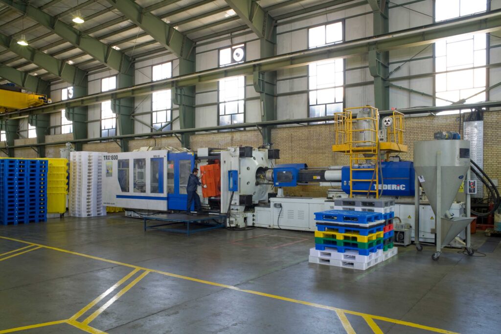 there is an injection machine in a factory which a worker take off the plastic pallet when the injection finishes